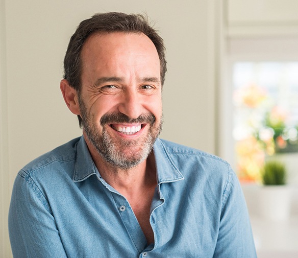 Man in blue shirt smiling with dental bridge in Flint