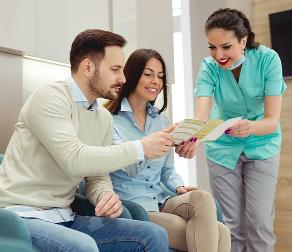 Dental team member giving patient dental insurance forms