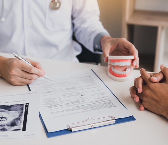 Dentist reviewing treatment plan paperwork holding smile model