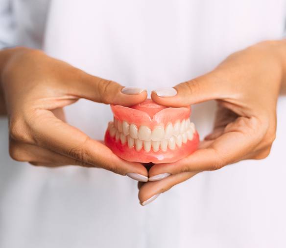 Hand holding full set of dentures