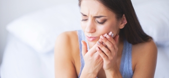 Woman in need of emergency dentistry holding cheek in pain