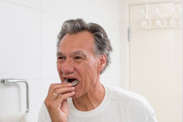 older man putting in occlusal splint before bed