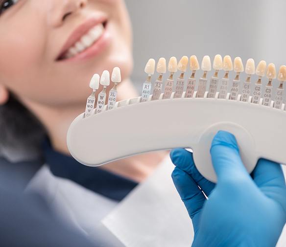 Dentist holding up veneer shades to patient's smile